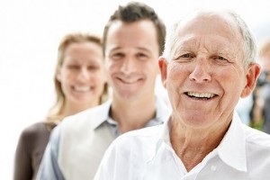 Closeup portrait of an old man smiling with his son and daughter in background against bright background